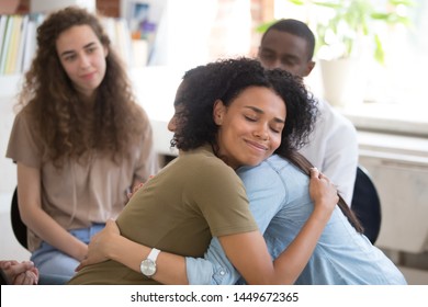 African American and Asian women embracing at group therapy session, empathy concept, psychological support, diverse friends overcome problem together, addiction treatment or team building close up