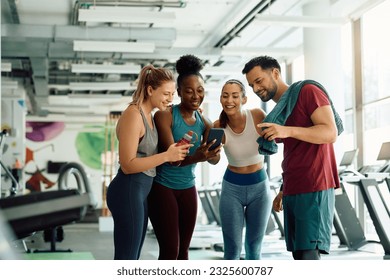 African American athlete using cell phone with her friends while exercising inn a gym.  - Powered by Shutterstock