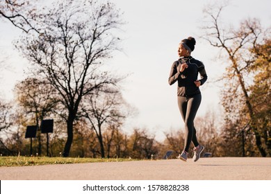 African American Athletic Woman Running In Autumn Day At The Park. Copy Space. 