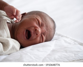 African American Baby Boy Crying On A White Bed.