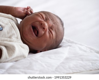 African American Baby Boy Crying On A White Bed.