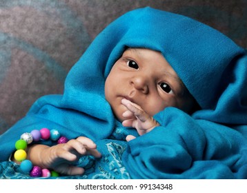 African American Baby Doll Portrait Lying Under Turquoise Blanket