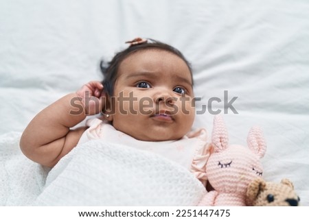 African american baby lying on bed covering with blanket at bedroom