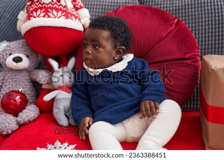 African american baby sitting on sofa with christmas decor at home