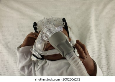 African American Baby Wearing A Nebulizer Mask. Childhood Asthma Concept Represented By A Reborn Doll: Lancashire, UK, 05-07-2021