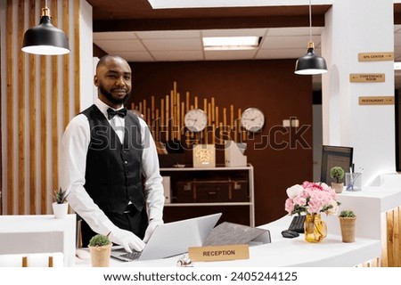 African american bellboy works at hotel, ensuring professional luxury concierge services for guests. Male resort employee providing assistance at check in, helping with accommodation.