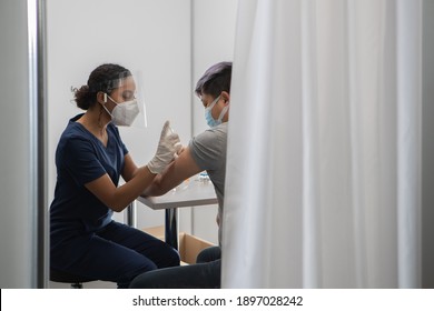 African American Black female Doctor prepares to administer vaccine to a Chinese patient in vaccination cabin. COVID-19 coronavirus vaccination - Powered by Shutterstock