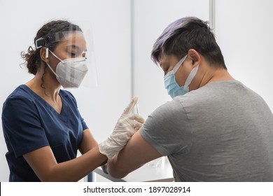 African American Black female Doctor prepares to administer vaccine to a Chinese patient in vaccination cabin. COVID-19 coronavirus vaccination - Powered by Shutterstock