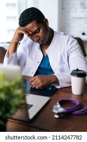 African American Black Man Doctor Is Analyzing History Disease Of Patient Using MRI Brain Head Scan Image While Working At Desk, Working On Laptop. Concept Of Medicine And Health Care.