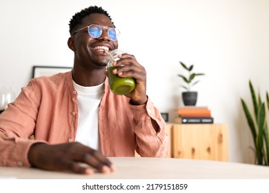 African American black man drinking healthy green juice with bamboo straw looking at camera. Copy space.
