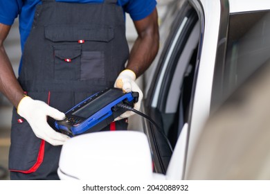 African American black people. Professional car mechanic repair service and checking car engine by Diagnostics Software computer. Expertise mechanic working in automobile repair garage. 