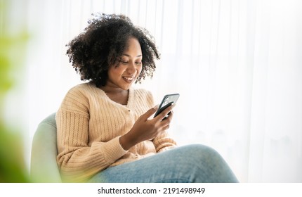 African American Black Woman Smile Use Tablet Smartphone In Blue Winter Sweater Work Home, Portrait Beauty  Girl Hygge Relax On Chair. Technology People Connection Digital Online Social Media Market