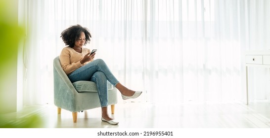 African American Black Woman Smile Use Tablet Smartphone In Blue Winter Sweater Work Home, Portrait Beauty  Girl Hygge Relax On Chair. Technology People Connection Digital Online Social Media Market