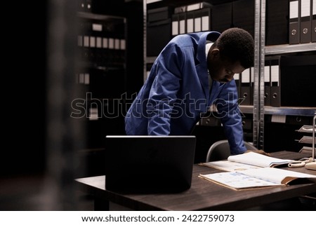 African american bookkeeper organizing management files, working late at night at accountancy report in storage room. Depository worker analyzing administrative documents, checking bureaucracy record