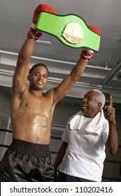 African American boxer holding championship belt with coach