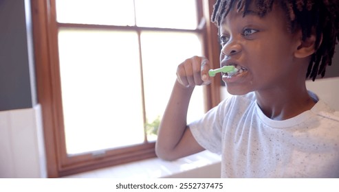 African american boy brushing teeth in bathroom at home, slow motion. Childhood, self care, hygiene and domestic life, unaltered. - Powered by Shutterstock