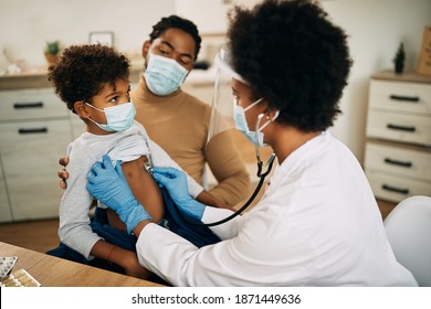 African American boy with face mask being examined by female pediatrician during medical apportionment at doctor's office. 