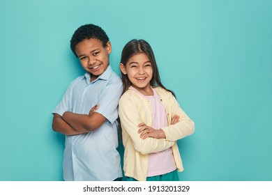 African American Boy And Latino Girl Standing Back To Back With Arms Crossed On A Turquoise Background