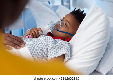 African american boy patient lying asleep in hospital bed wearing ventilator mask. Hospital, medical and healthcare services. - Powered by Shutterstock