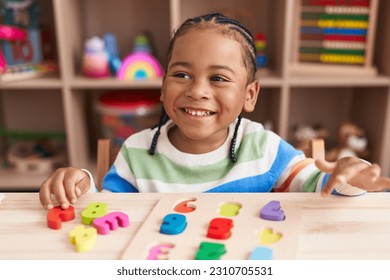 African american boy playing with maths puzzle game sitting on table at kindergarten - Shutterstock ID 2310705531