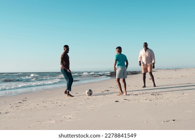 African american boy playing soccer with father and grandfather at beach against clear sky. Copy space, unaltered, multigeneration family, together, childhood, retired, nature, vacation, enjoyment. - Powered by Shutterstock