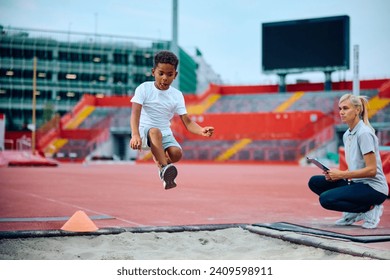 African American boy practicing long jump at athletics club at the stadium. - Powered by Shutterstock