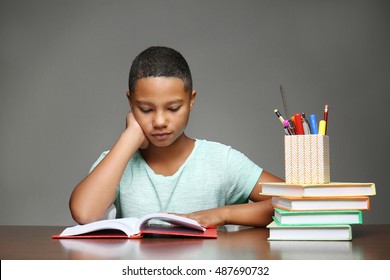 African American boy reading book on grey background