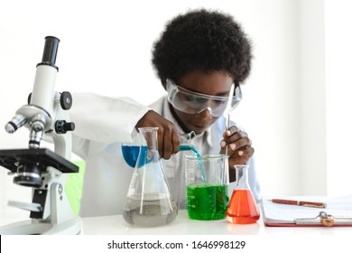 African american boy students learning and doing a chemical experiment and holding test tube in hands in science class on the table.Education concept - Powered by Shutterstock