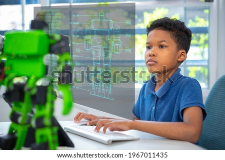 An african american boy use computer program robot kit.
