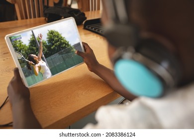 African american boy wearing headphones at home watching female tennis player on tablet. sports, competition, entertainment and technology concept digital composite image. - Powered by Shutterstock