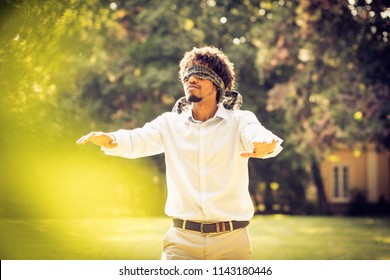 African American business man with blindfolded eyes in nature.
