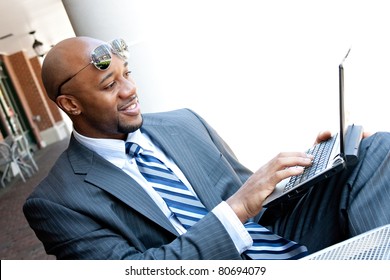 An African American Business Man In His Early 30s Using His Laptop Or Netbook Computer Outdoors With Copy Space For Your Text.