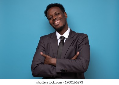 African American Business Man In Suit With Folded Arms. Studio Shot On Blue Wall.
