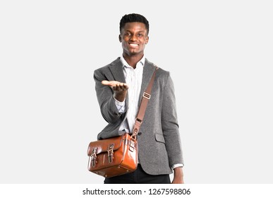 African american business man traveling with suitcases holding copy space imaginary on the palm to insert an ad on isolated grey background