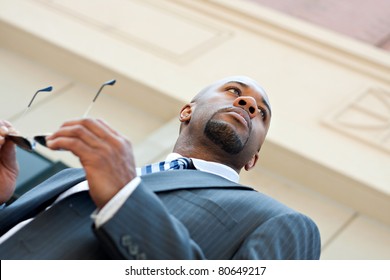 An African American Business Man Wearing His Sunglasses And Business Suit In The City.