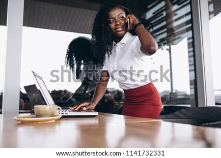 African american business woman with computer and phone in a cafe