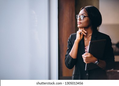 African american business woman holding laptop and standing by the window