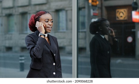 African american business woman speaking mobile phone go to office outdoors. Serious young afro girl businessperson using smartphone digital app device answering call walking calling on city street