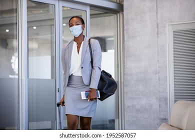 African American Business Woman Walking With Surgical Mask During Covid-19 Pandemic In Airport. Happy Mature Black Woman Walking At Terminal With Luggage And Passport Wearing Protective Face Mask.