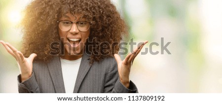 African american business woman wearing glasses celebrating crazy and amazed for success with arms raised and open eyes screaming excited. Winner concept