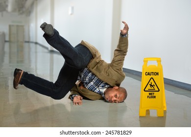 African American businessman falling on wet floor in office