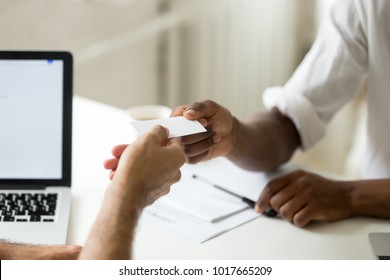 African american businessman giving visiting card to caucasian partner or client, black entrepreneur offering personal contact information to customer, business introduction concept, close up view