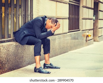 African American Businessman In New York. Dressing In Black Suit, Tie, Leather Shoes, Young Black Guy Sitting On Window On Street, Bending Back, Hands Covering Head, Tired, Sad. Instagram Effect.