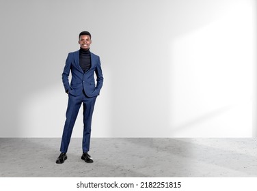 African American businessman wearing formal suit is standing in hands in pocket pose near empty white wall in background. Concept of model, successful business person - Shutterstock ID 2182251815