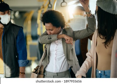 African American businesswoman coughing into elbow while traveling by public transport.  - Powered by Shutterstock