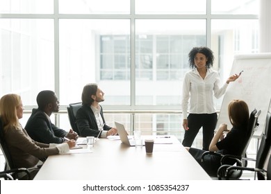 African american businesswoman giving presentation to executive team in meeting room, black business coach or employee working with flipchart reporting about work result, explaining new project idea