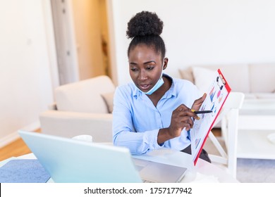 African american businesswoman having video conference while in quarantine during COVID-19 pandemic. Analyzing stock market chart and key performance indicators via video call - Powered by Shutterstock