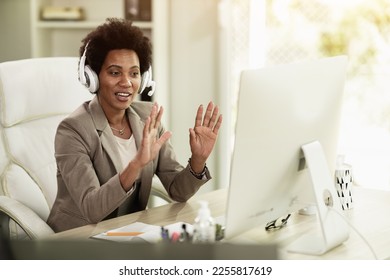 African American businesswoman with headphones having video call while sitting in an office alone at work. - Shutterstock ID 2255817619
