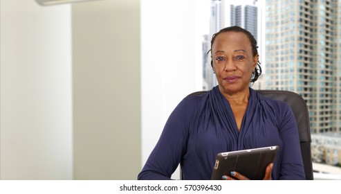 An African American businesswoman holding a tablet in her Chicago office