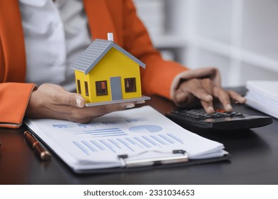 African American businesswoman with house model, Real estate agent and customer discussing for contract to buy house. - Powered by Shutterstock